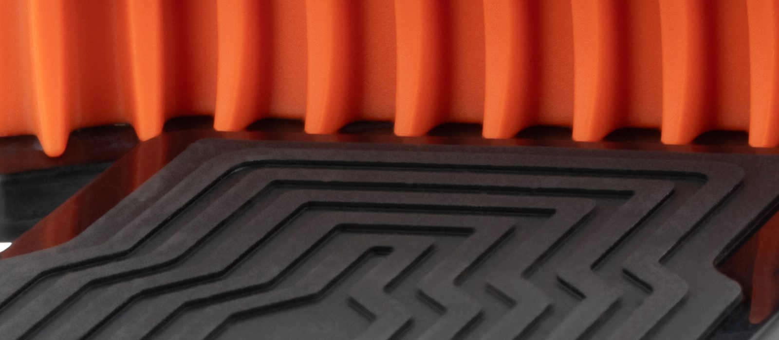 Detail van een Origin-telefoonhouder: oranje klemrand op een zwart profiel
